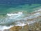 Waves of turquoise blue Aegean Sea crashing on the rocks at Mykonos