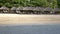 Waves of the warm sea run on the sandy beach of the tropical resort with umbrellas and chaise lounges