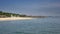 Waves of the warm sea run on the sandy beach of the tropical resort with umbrellas and chaise lounges