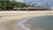 Waves of the warm sea run on the sandy beach of the tropical resort with umbrellas and chaise lounges