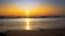 Waves wash up onto the beach as the sun sets down