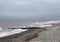 Waves and wooden breakwaters in the sea at thornton cleveleys near blackpool on an overcast cloudy day