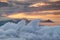 Waving clouds, jagged peaks and orange sky above morning mist