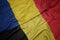 waving colorful flag of belgium and national flag of romania