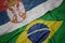 waving colorful flag of brazil and national flag of serbia