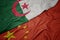 waving colorful flag of china and national flag of algeria