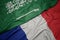 waving colorful flag of france and national flag of saudi arabia