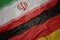 waving colorful flag of germany and national flag of iran