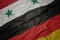 waving colorful flag of germany and national flag of syria