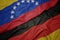 waving colorful flag of germany and national flag of venezuela