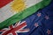 waving colorful flag of new zealand and national flag of kurdistan