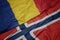 waving colorful flag of norway and national flag of romania