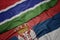 waving colorful flag of serbia and national flag of gambia