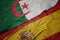 waving colorful flag of spain and national flag of algeria