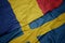 waving colorful flag of sweden and national flag of romania