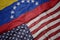 waving colorful flag of united states of america and national flag of venezuela