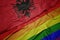 waving colorful gay rainbow flag and national flag of albania