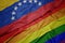 waving colorful gay rainbow flag and national flag of venezuela