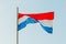 Waving colorful Netherlands flag on blue sky.