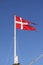 Waving Danish Royal Flag with blue sky and copy space