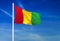 Waving flag of Guinea on the blue sky background