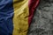 waving flag of romania on the old khaki texture background. military concept