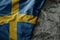 waving flag of sweden on the old khaki texture background. military concept