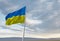 Waving Ukraine flag against a blue sky with clouds and empty space for text.