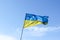 Waving Ukrainian yellow-blue flag against a blue sky