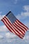 Waving USA flag in blue and cloudy sky. American symbol of fourth of July Independence Day