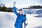 Waving young woman with snowboard in her hand