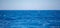 Wavy ocean water surface deep blue color, small wave with foam, blue sky background