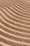 Wavy pattern on a beach in the summer. The textured surface of sand on the beach after a strong wind in the form of waves close up