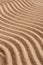 Wavy pattern on a beach in the summer. The textured surface of sand on the beach after a strong wind in the form of waves close up