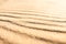 Wavy pattern sandy texture of clean beach sand surface. Coastline travel background with copy space, selective focus