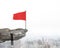 Wavy red flag on top of cliff with Businessman hanging