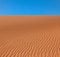 Wavy rippled desert or beach sand texture and blue sky