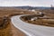 Wavy tarmac road framed with brown meadows at early spring.