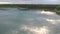 Wavy water surface with blurred sky reflection. Rippled water texture with blurry reflection in bright sunlight. Calm