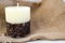 Wax beautiful light beige candle with unflavored wick from below decorated with coffee beans on the background of old brown canvas
