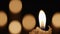 Wax burning candle flickers in dark on a black background with blurred candlelight bokeh effect. Background or