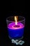 A wax candle on a black background. Close-Up Of A Burning Purple Candle. candles.