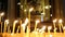 Wax candles burn in the dark in the Orthodox Church framed with an ancient icon