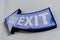 This Way Exit written on a decorative blue wooden arrow hanging on a wall