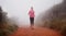 The only way she likes to run. Shot of a woman running on a trail on a misty morning.