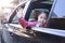 On the way to school, the little girl stretched out his hand from the car window, laughing and smiling. Asian little girl smiling