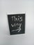 This way written on a chalkboard on a white background