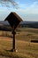 Wayside cross with carvings in shadow and a simple Birch cross