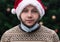 Wearing a mask incorrectly. Close up Portrait of man wearing a santa claus hat, xmas sweater and medical mask with emotion.