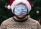 Wearing a mask incorrectly. Close up Portrait of man wearing a santa claus hat, xmas sweater and medical mask with emotion.